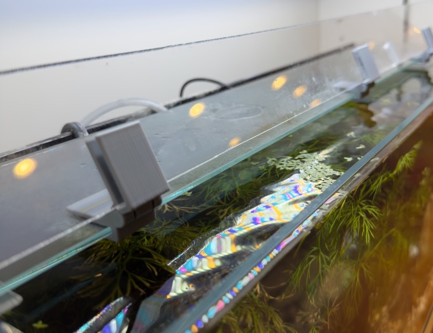 Hinge between acrylic and glass panels of aquarium lid